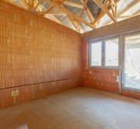 A room in a family house with brick walls and a raw floor.