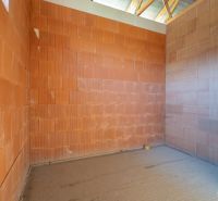 An unplastered wall in the interior of a family house bathroom with brick blocks.