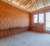 A room in a family house with a window, a brick wall, and a floor with a wooden design.
