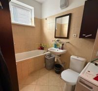 A bathroom in a 2-room apartment with a shower, sink, and washing machine.