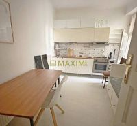 A kitchen in a 3-room apartment with a dining table and white furniture.