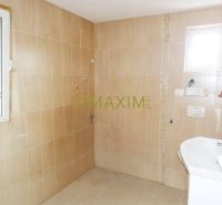 A bathroom in a cottage with beige tiles and a window letting in natural light.
