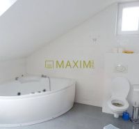Bathroom with a bathtub and toilet in a cottage with an attic, white tiles.