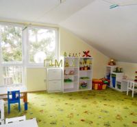A children's playroom with a colorful carpet and tables full of toys and shelves in a cottage.