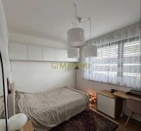 Bedroom in a 3-room apartment with wood-patterned flooring, carpet, desk, bed.