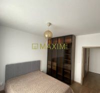 A bedroom in light shades with a bed, wardrobe, and wooden decor flooring.
