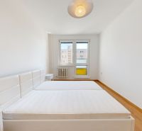 A bright bedroom with a large bed and a wooden decor floor in a two-room apartment.
