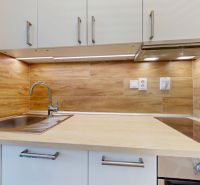 A kitchen with wood decor and appliances in a 2-room apartment.