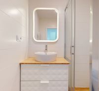 Bathroom with a shower and a sink on a wooden decor in a 2-room apartment.