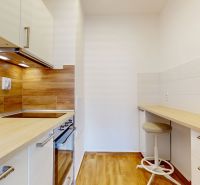 A kitchen with a wooden decor floor and tiles, simple design in a 2-room apartment.