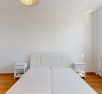 A bright bedroom with white furniture and a wood-decor floor in a 2-room apartment.