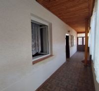A hallway in a family house with a wooden decor floor and curtains on the windows.