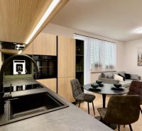 A kitchen in a 2-room apartment with a wooden decor floor and gray seating.