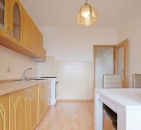 A kitchen with a wooden countertop, a floor with a wooden decor, a dining table, and chairs in a 3-room apartment.