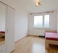A bright room with a wardrobe and a bed, a floor with a wooden decor in a 3-room apartment.