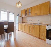 A kitchen in a 3-room apartment with a kitchen unit, dining table, and a floor with a wooden decor.
