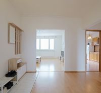 Viewing of the entrance hall and living room with wood-patterned flooring in a 3-room apartment.