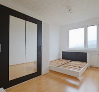 A bright bedroom with a bed and a wardrobe, a floor with a wooden decor in a 3-room apartment.