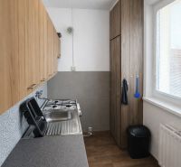 A kitchen in a 2-room apartment with a wooden decor floor and built-in furniture.