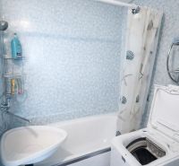 Bathroom in a 2-room apartment with a bathtub and a top-loading washing machine.