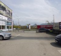 Parking lot at the commercial premises on Masarykova 22 in Prešov with cars and advertising signs.