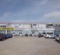 The exterior of commercial premises at Masarykova 22 in Prešov with a parking lot in front of the buildings.