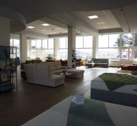 Bright commercial spaces with wood-decor flooring, equipped with sofas and beds.