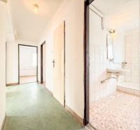 A hallway with a green floor, entrance to the bathroom and a room in a 3-room apartment.