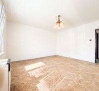 A spacious room with a window and a floor with a wooden decor in a 3-room apartment.