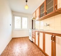 A kitchen with a wooden decor floor in a 3-room apartment with a simple kitchen unit.