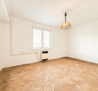A room with white walls, a floor with a wooden decor, a pendant light in a 3-room apartment.