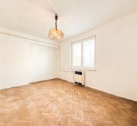 A room with a wooden decor floor and antique lighting in a 3-room apartment.