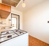 A kitchen in a 3-room apartment with a gas stove and wooden floor decor.