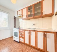 A kitchen with wooden cabinets, a wooden-patterned floor, and a stove in a 3-room apartment.
