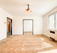 Living room with wood-patterned flooring in a 3-room apartment, large windows, glossy ceilings.