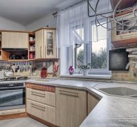 A kitchen in a family house with a kitchen unit, a stove, and a view through the window.