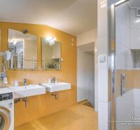 A bathroom in a family house with a double sink, shower, and washing machine.