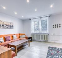 Living room in a family house with an orange sofa and wood-patterned flooring.