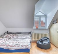 Bedroom in a family house with a bed, a pocket chair, and a floor with a wooden decor.