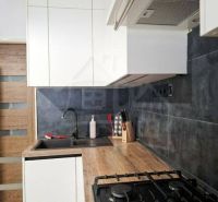 A kitchen in a family house with a wooden decor floor and white cabinets.