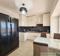 A modern kitchen in a family house with a large refrigerator and a dining table.