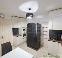 A kitchen in a family house, light cabinetry, black refrigerator, wooden decor on the countertop.