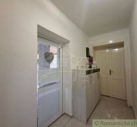 A hallway in a family house with white walls and a cabinet by the door.