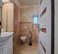 A bathroom in a family house with a sink, toilet, and window.