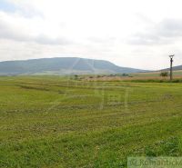The landscape in Smilno with agricultural and forest land and a view of the mountains.
