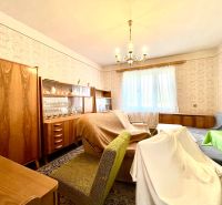 Living room in a family house with retro furniture and patterned wallpaper.