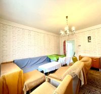 A living room in a family house with furniture covered with fabrics and patterned wallpaper.