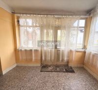 A family house with windows with lace curtains and a stone floor.