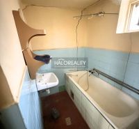 A bathroom in a family house with a bathtub, a sink, and light blue ceramic tiles.