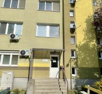 Entrance to an apartment building in Komárno, with a staircase and air conditioning units on the facade.